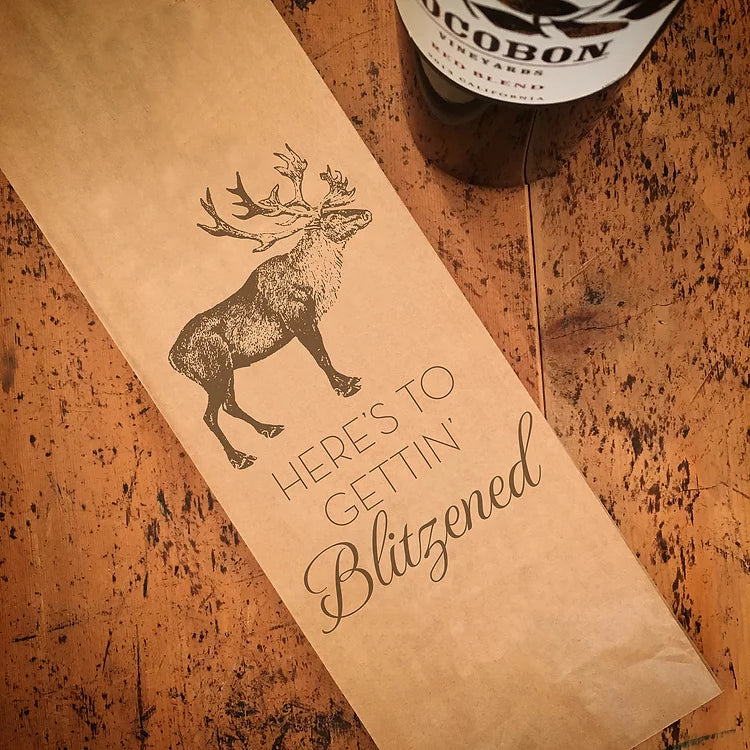 Vinpåse i papper med julmotiv. Ren och texten "Here's to gettin Blitzened"