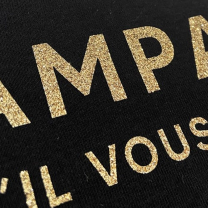 Svart t-shirt med guldglittrig text "Champagne s'il vous plait"