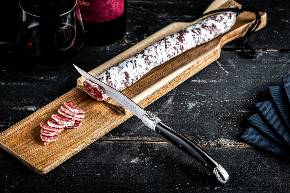 Korvskärbräda med kniv. Akacia. Svart Laguiolekniv. Inspirationsbild med korv